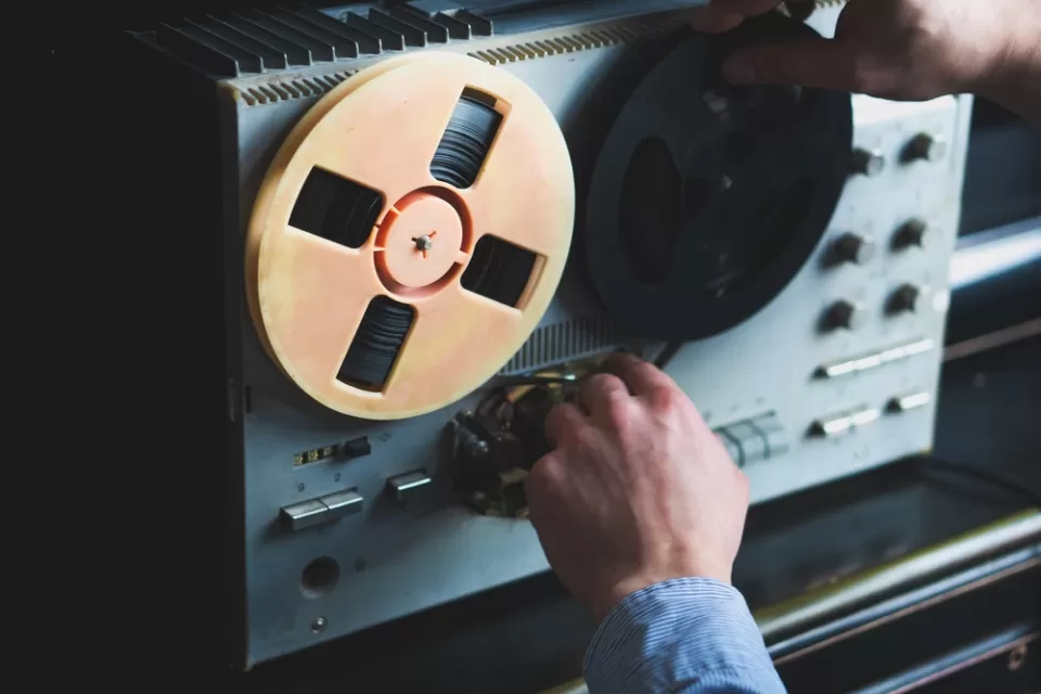 Close-up of reel-to-reel tape recorder with hand turning knob